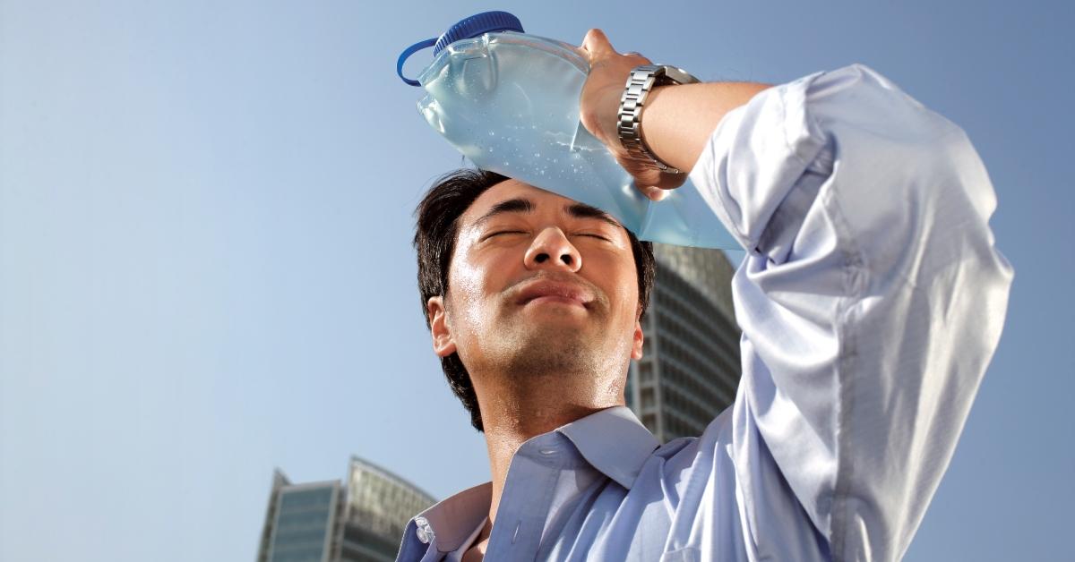 Man holding a water bottle up to his forehead.