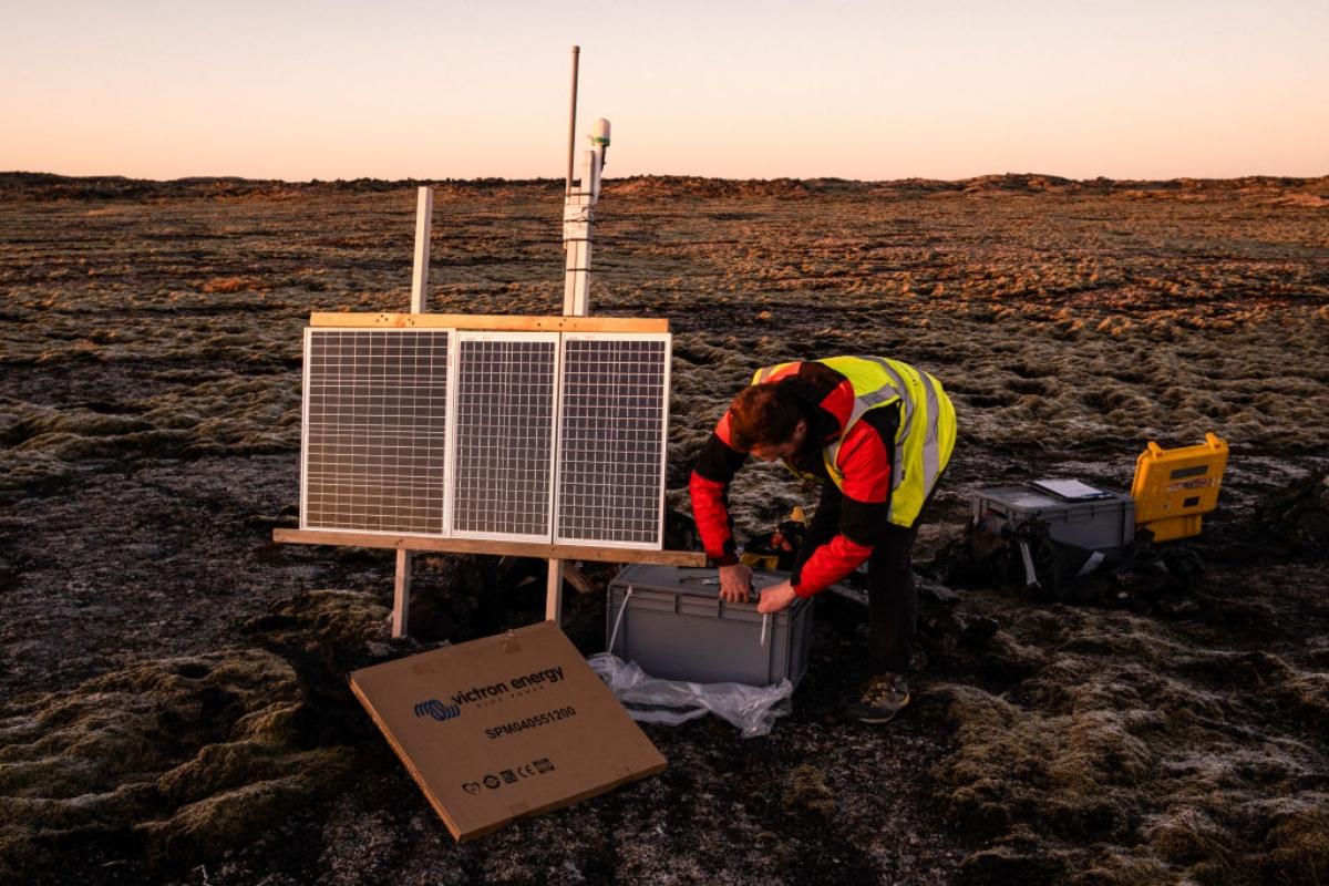 scientist installing seismograph on a barren landscape