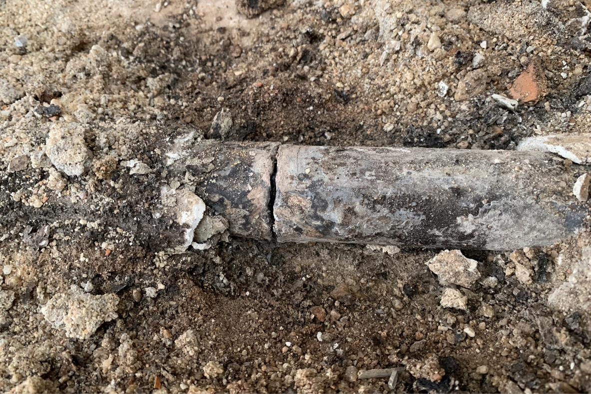 A broken lead pipe exposed from underground